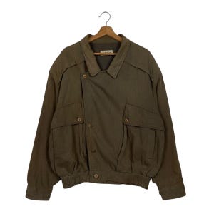 May include: A brown jacket with a button closure, two front pockets, and a collared neckline. The jacket is hanging on a wooden hanger. The jacket has a ribbed hem and cuffs.