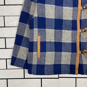 May include: A blue, grey, and white checked jacket with leather detailing and metal clasps. The jacket has a classic plaid pattern and a tailored fit. The leather accents add a touch of sophistication to the outerwear.
