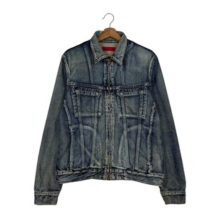 Può includere: Giacca di jeans blu con zip, due tasche sul petto e colletto. La giacca è appesa a una gruccia di legno su sfondo bianco. Il denim ha un aspetto sbiadito e usurato.