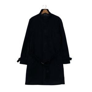 May include: A black trench coat with a belt, hanging on a wooden hanger. The coat has a collar and long sleeves. The belt is fastened at the waist. The coat is made of a dark fabric.
