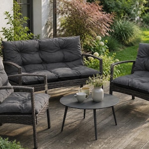 Può includere: Set di mobili da giardino grigio scuro composto da un divano a due posti, due poltrone e un tavolino rotondo. I cuscini sono grigio scuro. Il set è posizionato su un decking in legno.
