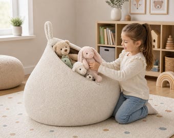 Funda tipo puf de bouclé para guardar peluches, color beige claro, ideal para habitaciones infantiles o como asiento para guardar juguetes blandos. 100 x 65 cm.