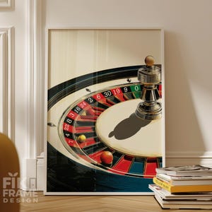 Könnte beinhalten: Ein gerahmter Druck mit einem Casino-Roulette-Rad mit roten, schwarzen und grünen Abschnitten. Ein Metall-Roulette-Marker befindet sich auf dem Rad. Die Zahlen sind deutlich sichtbar. Der Druck wird auf einem Holzboden angezeigt.