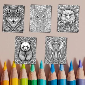 May include: Five black and white animal illustrations: a wolf, deer, eagle, panda, and elephant. Each animal is set against a detailed mandala background. Below, a row of colorful pencils with sharpened tips are arranged.
