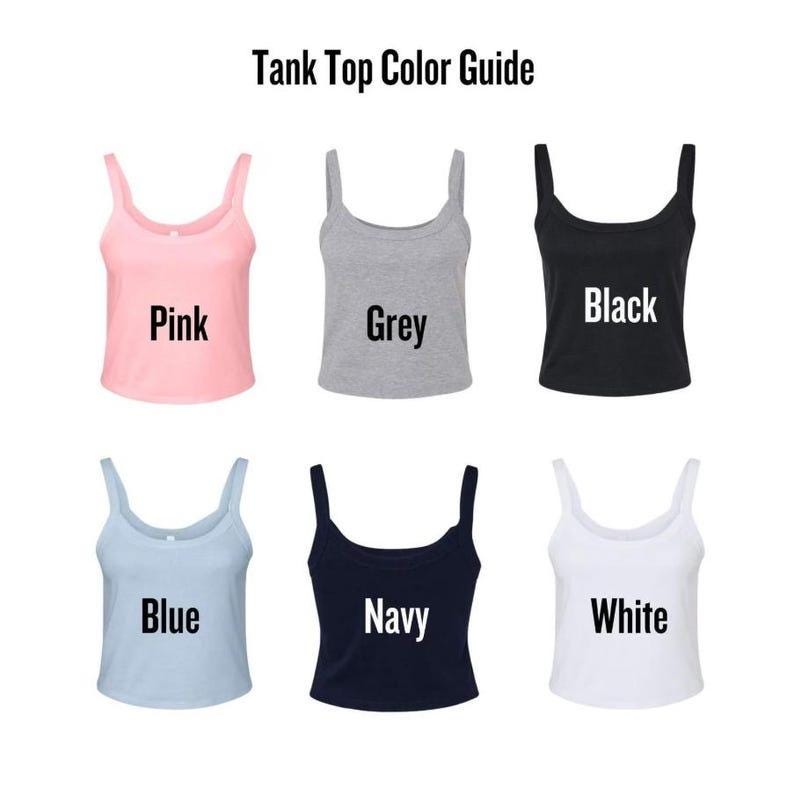 May include: A color guide for tank tops, featuring six different colors: pink, grey, black, blue, navy, and white. Each tank top is displayed with its corresponding color name in a bold, sans-serif font. The text "Tank Top Color Guide" is at the top.