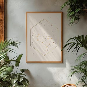 Pode incluir: Uma impressão de arte de parede emoldurada apresentando um design de constelação dourada contido dentro de um contorno hexagonal dourado fino. A obra está sobre um fundo creme claro, acentuado com pequenos pontos dourados e luas crescentes.