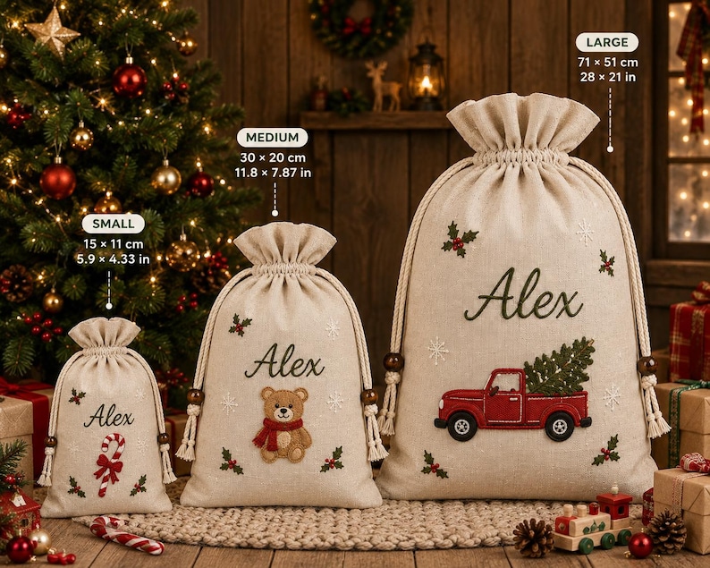 May include: Three beige drawstring gift bags in small, medium, and large sizes. The small bag features a candy cane, the medium a teddy bear, and the large a red truck carrying a tree. Each bag is embroidered with the name Alex and holly.
