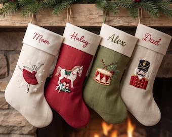 May include: Four Christmas stockings hanging in a row. The first is cream with a red ballerina, the second is red with a white horse, the third is olive green with a drum, and the fourth is cream with a nutcracker. Each has a name embroidered on the cuff: Mom, Haley, Alex, and Dad.