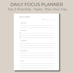 May include: A white Daily Focus Planner with the text "DAILY FOCUS PLANNER" at the top. The planner includes sections for "Main Focus," "Top 3 Tasks," and "Other Tasks." The planner also has a section to "Plan Your Day" and "Notes."