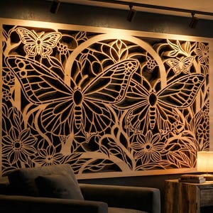 May include: A large wooden wall art piece with a detailed butterfly and floral design. The artwork is illuminated, highlighting the intricate cut-out patterns. The piece is a warm, natural wood colour, adding a decorative element to the room.