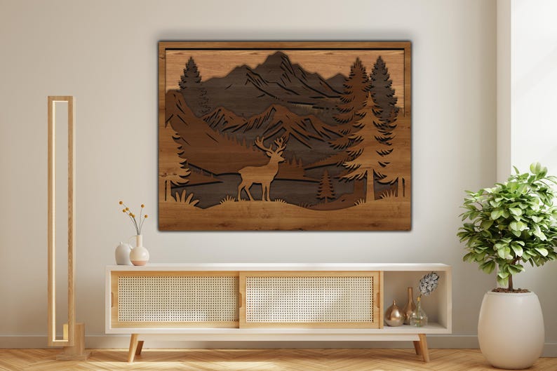 May include: A wooden wall art piece depicting a forest scene with a deer, mountains, and trees. The artwork is made of layered wood in shades of brown and tan, creating a 3D effect. The piece is rectangular and mounted on a light-colored wall.