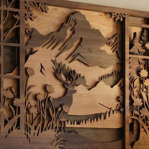May include: A wooden wall art piece featuring a layered design of a mountain landscape with a deer. The artwork is crafted from various shades of brown wood, creating a three-dimensional effect. The design includes trees, flowers, and a mountain range.