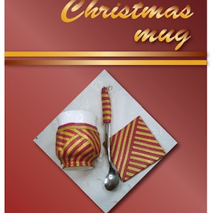 Puede incluir: Una taza de cerámica blanca con un diseño a rayas rojo y dorado, una cuchara a juego a rayas rojo y dorado y una servilleta a rayas rojo y dorado. El texto "Merry Christmas mug" está escrito en letras doradas sobre un fondo rojo.