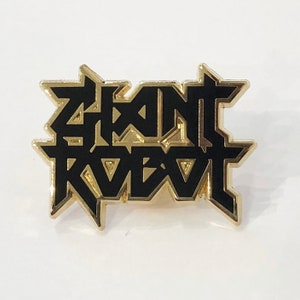 May include: Black and gold metal pin with the text "Giant Robot" in a stylized font.