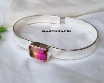 May include: A silver cuff bracelet with a rectangular, multi-colored gemstone. The gemstone displays shades of pink, orange, and yellow. The bracelet is on a white surface. The text "MAYAJEWELLERYART925" is visible.