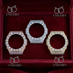 May include: Three watch bezels with a circular opening, each encrusted with small, sparkling stones. The bezels are in shades of silver, gold, and rose gold, with blue and clear stones. The word "UNICORN" is printed on the top and bottom of the image.