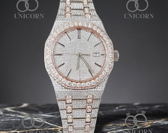 May include: A luxury wristwatch with a silver-colored face and band, encrusted with numerous small, sparkling stones. The watch has a rose gold bezel and accents, and a date display at the 3 o'clock position. The watch is displayed on a marble surface.
