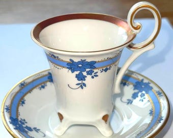 Taza y platillo vintage de porcelana Weimarer con base: diseño floral azul, blanco y dorado, pintados a mano, hechos en Alemania.