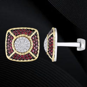 May include: A pair of square cufflinks with a gold-colored border. The center features a circle of small white stones, surrounded by a square of small red stones. The cufflink post is silver.
