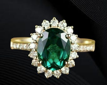May include: A gold ring featuring a large, oval-cut emerald gemstone surrounded by a halo of smaller, round diamonds. The ring's band is also adorned with small diamonds, creating a sparkling effect against a dark background.