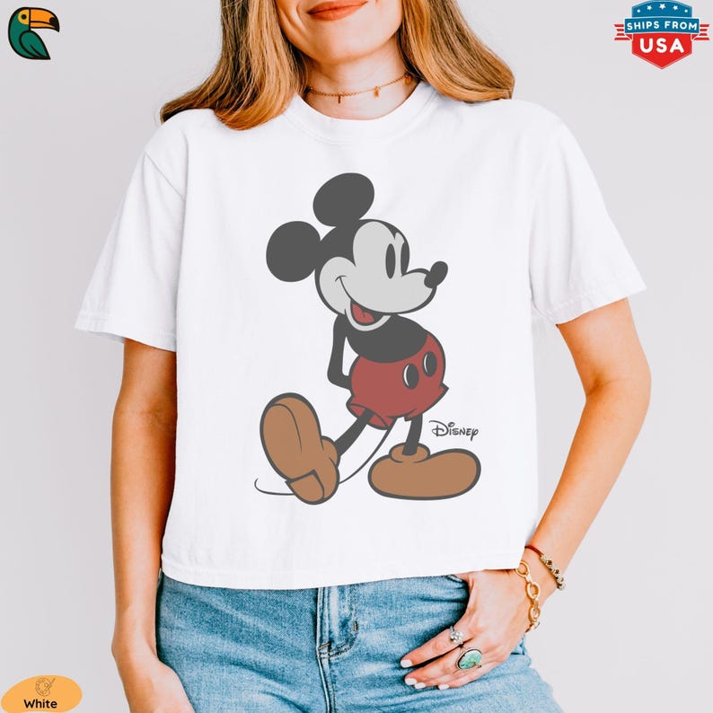 K&ouml;nnte beinhalten: Wei&szlig;es T-Shirt mit einer klassischen Mickey Mouse-Illustration. Die Zeichentrickfigur ist in Schwarz, Rot und Braun dargestellt. Das Disney-Logo befindet sich unten rechts. Ein l&auml;ssiges Oberteil f&uuml;r Disney-Fans.