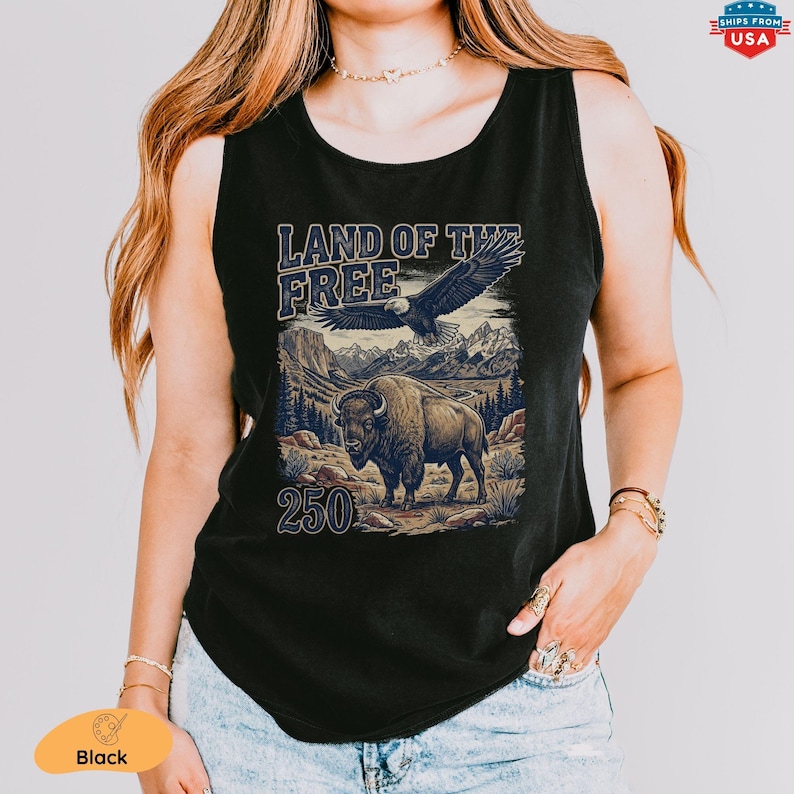 May include: Black tank top featuring a graphic with the text "LAND OF THE FREE" above an eagle and a bison in a mountain landscape. The number "250" is below the bison. The tank top is sleeveless.