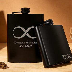 Puede incluir: Dos petacas de metal negro mate con tapones de rosca. La petaca más grande presenta un símbolo de infinito grabado sobre el texto "Connor and Haylee" y "06-19-2027". La petaca más pequeña tiene las iniciales "DK" grabadas en la parte inferior.