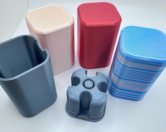 May include: A collection of five rectangular containers with rounded corners, including a dark gray open holder, a light beige closed container, a red closed container, a blue and gray striped closed container, and a small dark gray four-slot insert.