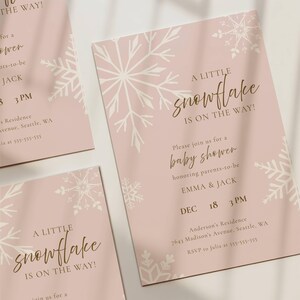 K&ouml;nnte beinhalten: Ein Set aus drei zartrosa Babyparty-Einladungskarten mit wei&szlig;en Schneeflocken-Illustrationen und goldenem Text, der A LITTLE SNOWFLAKE IS ON THE WAY lautet, zu Ehren von Emma und Jack am 18. Dezember um 15 Uhr in Seattle.
