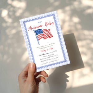 K&ouml;nnte beinhalten: Eine Babyparty-Einladung mit patriotischem Thema. Die Einladung zeigt eine Illustration der amerikanischen Flagge und die Worte "American Baby" in roter Schrift. Die Einladung hat einen blau-wei&szlig; karierten Rand und enth&auml;lt Eventdetails.