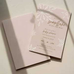 A little snowflake is on the way, girl baby shower template featuring white snowflakes on a dusty pink background with editable text