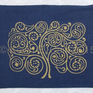 May include: A dark blue linen pillow cover with a gold metallic design of a stylized tree with intricate swirls and leaves.