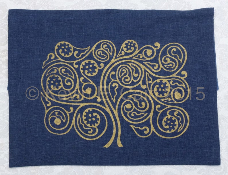 May include: A dark blue linen pillow cover with a gold metallic design of a stylized tree with intricate swirls and leaves.