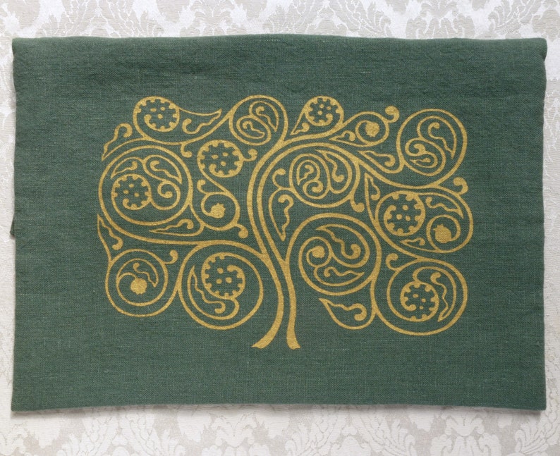 May include: A green linen pillow with a gold metallic design of a stylized tree with swirling branches and leaves.