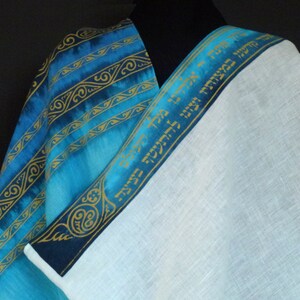 May include: A blue and white prayer shawl with gold Hebrew text on the border. The shawl is made of linen and has a blue and gold patterned design.