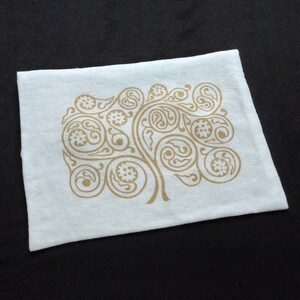 May include: White cotton tea towel with a gold paisley design printed on it. The design is a stylized tree with branches and leaves.