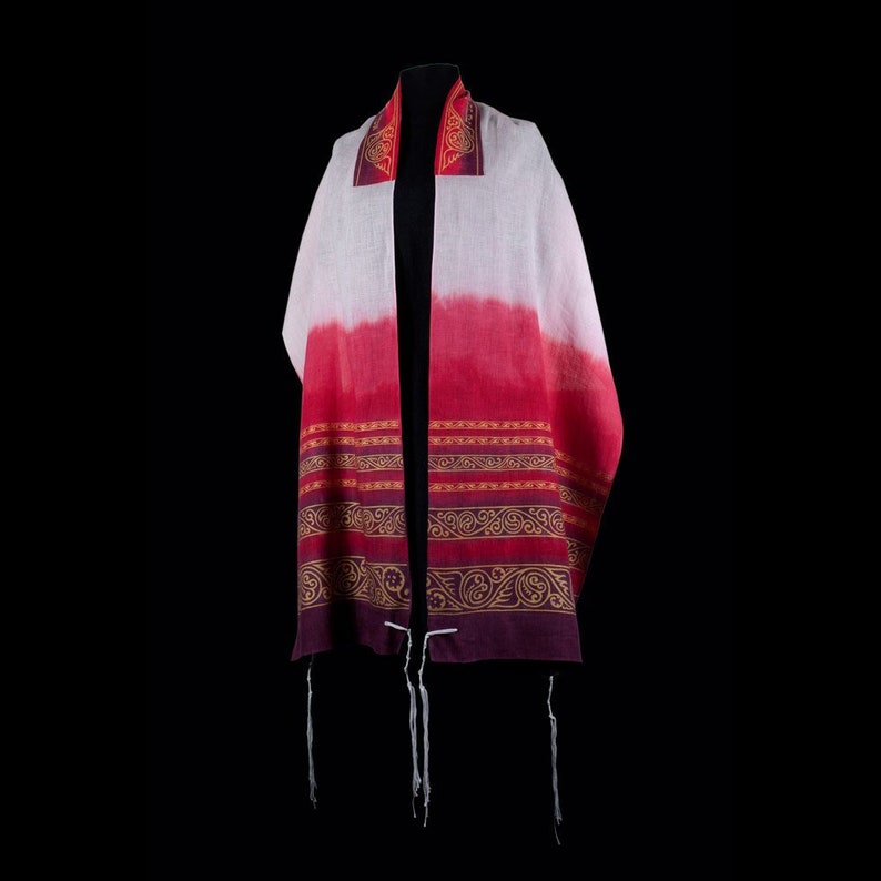 May include: A white and red prayer shawl with gold and purple trim and tassels. The shawl has a gradient design with a white top and red bottom. The trim features intricate patterns.