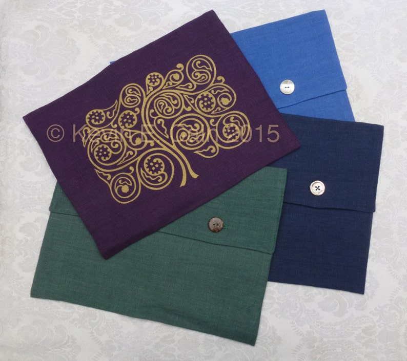 May include: Four fabric envelopes with a button closure. The envelopes are in different colors: green, purple, blue, and navy blue. The purple envelope has a gold design of a tree with swirling branches.