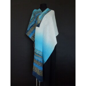 May include: A blue and white prayer shawl with gold embroidery. The shawl is made of a soft, lightweight fabric and is perfect for prayer or meditation.