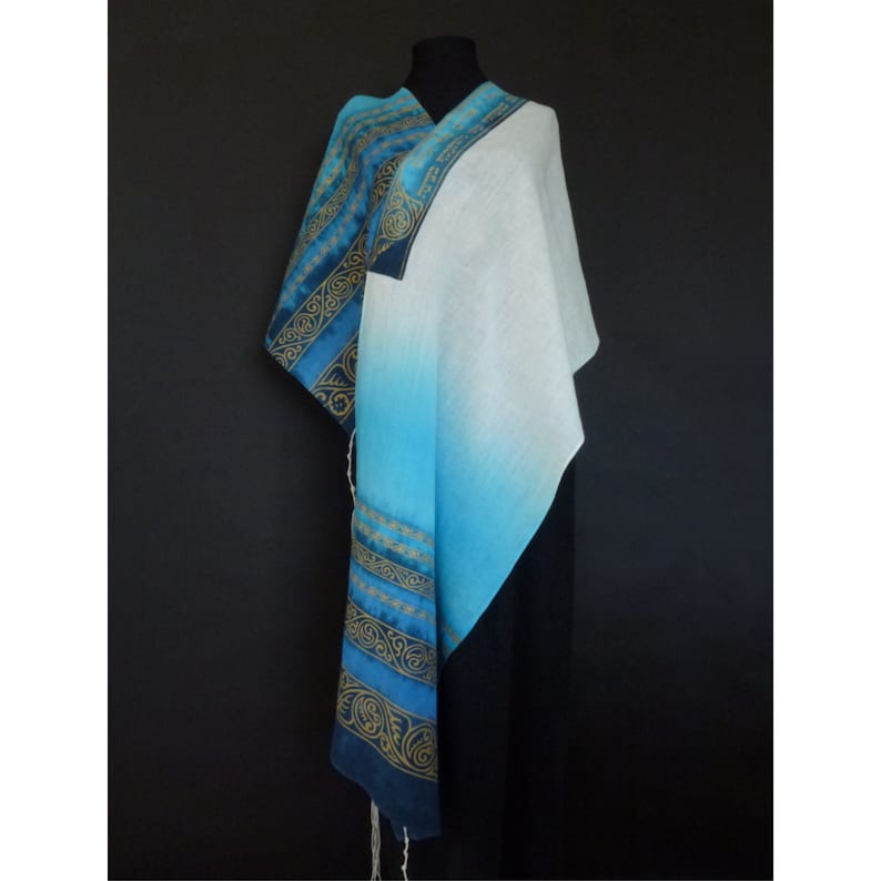 May include: A blue and white prayer shawl with gold embroidery. The shawl is made of a soft, lightweight fabric and is perfect for prayer or meditation.