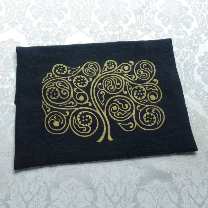 May include: A black linen clutch bag with a gold-colored paisley design. The design features intricate swirls and patterns.