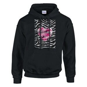 Op de afbeelding: Zwarte hoodie met een roze camouflage hart design. Het hart staat centraal op een zebra-gestreepte achtergrond. De tekst "RESCENTASHELL" is op het hart gedrukt.