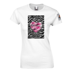 Op de afbeelding: Wit T-shirt met een roze camouflage hart ontwerp op een zebraprint achtergrond. De tekst "EXCELLENT AS HELL" is op het hart gedrukt. Het shirt heeft korte mouwen en een ronde hals.