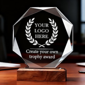 Puede incluir: Un trofeo de vidrio transparente y facetado con el texto "YOUR LOGO HERE" dentro de una corona de laurel. La base es de madera oscura, y el texto "Create your own trophy award" está debajo.