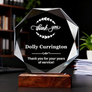 Może przedstawiać: Fasetowana kryształowa nagroda z czarnym wnętrzem, z napisami "thank you" i "Dolly Currington". Nagroda stoi na drewnianej podstawie, z tekstem "Thank you for your years of service!"