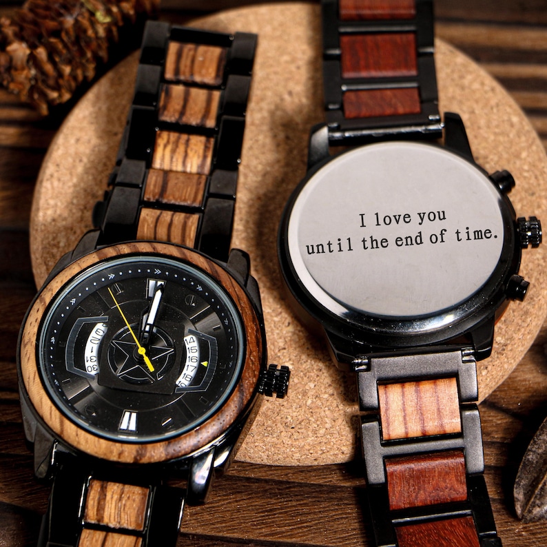 K&ouml;nnte beinhalten: Zwei Holzarmbanduhren mit schwarzen Metallakzenten. Eine Uhr hat ein schwarzes Zifferblatt mit gelbem Zeiger und Datumsanzeige. Die andere Uhr tr&auml;gt die Aufschrift "I love you until the end of time."