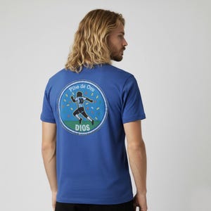 Può includere: T-shirt blu reale con grafica circolare sul retro. La grafica presenta un calciatore in bianco e nero, le parole "Pibe de Oro" e "DIOS" e coriandoli. La maglietta è a maniche corte.