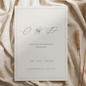 Puede incluir: Una tarjeta de invitación minimalista con un diseño floral y el texto "INVITE YOU TO CELEBRATE THEIR LOVE". La fecha "28 08 2028" y la dirección "123 ANYWHERE ST., ANY CITY" también se muestran. La tarjeta está sobre un fondo de tela neutra.