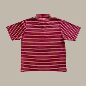May include: A maroon polo shirt with white horizontal stripes. The short-sleeved shirt has a collared neckline and is made of a ribbed fabric. The shirt is laid flat on a neutral background.