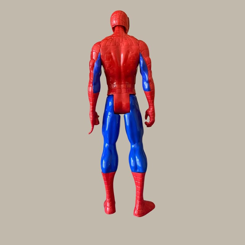 Puede incluir: Una figura de acci&oacute;n de Spider-Man roja, azul y negra, vista desde atr&aacute;s. La figura tiene cabeza y torso rojos, piernas y brazos azules, y pies y manos rojos. La figura est&aacute; de pie.
